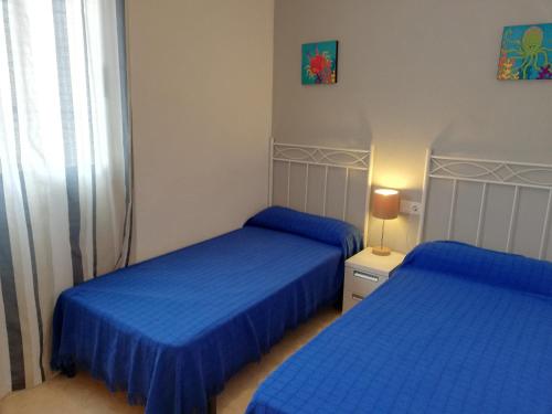 two beds in a room with blue sheets at Delfines Solo Familias Serviplaya in Playa de Xeraco