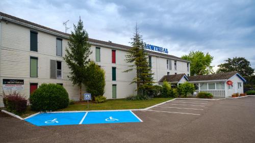 a parking lot in front of a building at Cit'Hotel Le Montreal in Châlons-en-Champagne