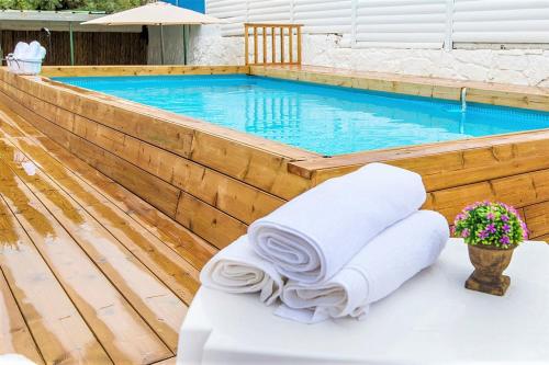 a pool with a stack of towels in front of it at אדם וחווה - סוויטות מפנקות עם ג'קוזי פרטי ובריכה במתחם מול נוף גלילי מושלם in Gornot HaGalil