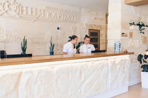 dos mujeres de pie detrás de un mostrador en un restaurante en Osonnya Karpaty 4*, en Skhidnytsya