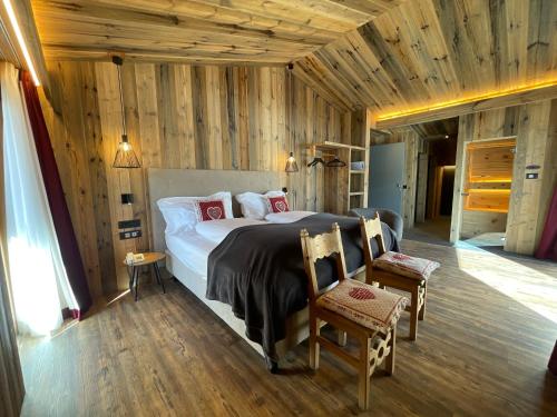 1 dormitorio con 1 cama grande y paredes de madera en Hotel Piccolo Tibet, en Livigno