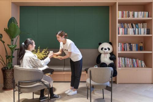 a woman is giving a woman a present in a waiting room at Atour Light Hotel Chunxi Road Subway Station Taikoo Li Chengdu in Chengdu