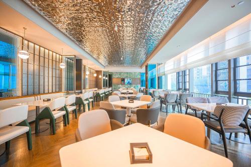a dining room with tables and chairs and windows at Atour Hotel Shenzhen Baoan Vanke Star City in Bao'an