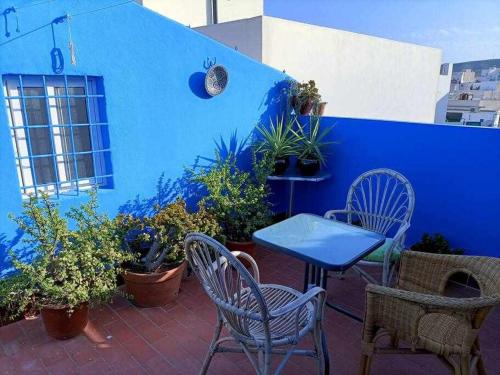 a patio with chairs and a blue wall with plants at Casa de pueblo in Carboneras