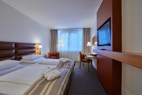 a hotel room with two beds and a flat screen tv at Hotel Bredeney in Essen