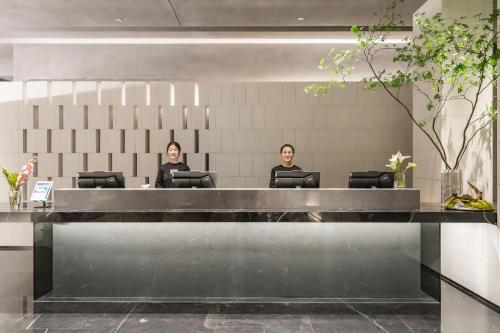 Duas mulheres sentadas numa secretária no átrio. em Atour S Hotel Shanghai Lujiazui Expo Center em Xangai