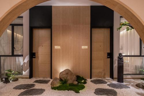 - un hall avec trois portes en bois et des rochers au milieu dans l'établissement Atour X Hotel Shenzhen Futian CBD Chegongmiao, à Shenzhen