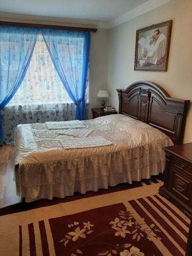 een slaapkamer met een bed en een raam met blauwe gordijnen bij Квартира в Гюмри in Gjoemri