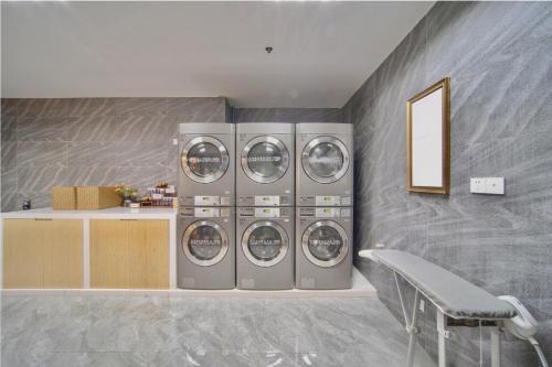 a laundry room with four washing machines and a bench at Atour X Hotel Shenzhen Futian CBD Chegongmiao in Shenzhen