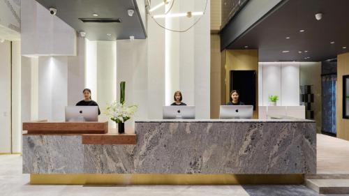 three people sitting at a reception desk with laptops at Atour S Hotel Beijing Zhongguancun Beiwai in Beijing