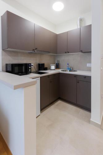 a kitchen with brown cabinets and a microwave at Black & White Apartment in Subotica