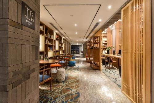 a corridor of a library with tables and chairs at Atour Hotel South Luogu Lane Beijing in Beijing
