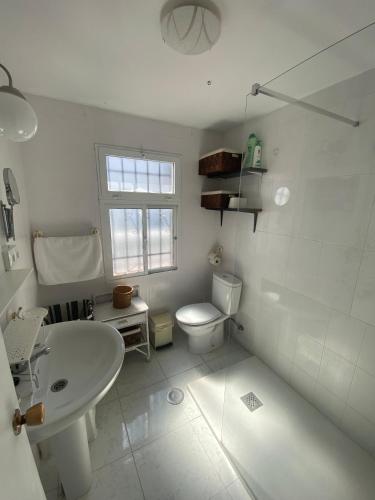 a white bathroom with a toilet and a sink at Casa Andrés in Arriate