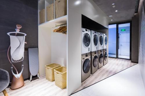 a laundry room with four washer and dryers at Atour Hotel Qingdao Fuzhou Road Sakura Town in Qingdao