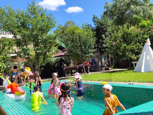 a group of children playing in the water at a swimming pool at Encounter Garden Great Wall Holiday Guesthouse in Beijing