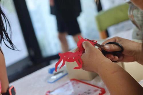 a person cutting a piece of paper with scissors at Encounter Garden Great Wall Holiday Guesthouse in Beijing