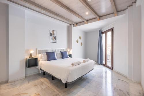 Dormitorio blanco con cama y ventana grande en Apartamentos Realejo Granada Centro 3000, en Granada