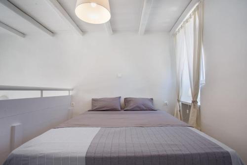 a bed in a white room with a window at Hidden Gem Authentic cycladic house in Paros in Márpissa