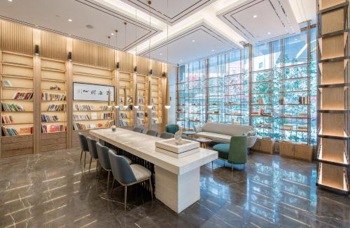 a library with a large table and chairs and bookshelves at Atour Hotel Shenzhen Baoan International Airport in Bao'an