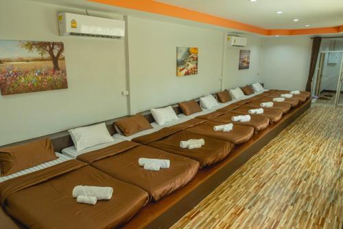 a room with a long row of brown beds at Apinya Resort Bangsarey in Ban Tao Than