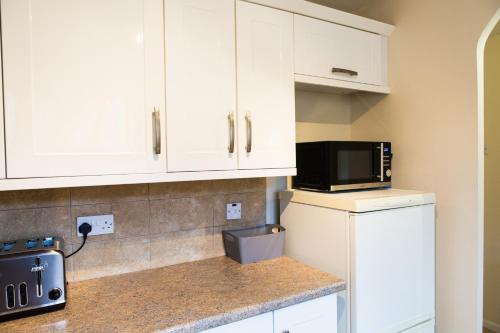 a kitchen with white cabinets and a microwave at Penny's Place in Plymouth