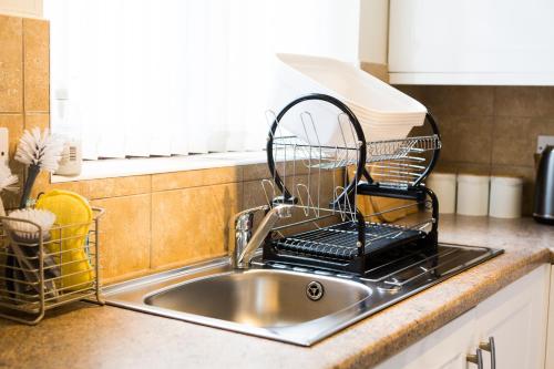 a dish drying rack sitting on a kitchen sink at Entire 2 Bedroom House near Derriford with Parking in Plymouth