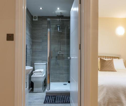 a bathroom with a shower and a toilet and a bed at Charnwood Guest House in Bracknell