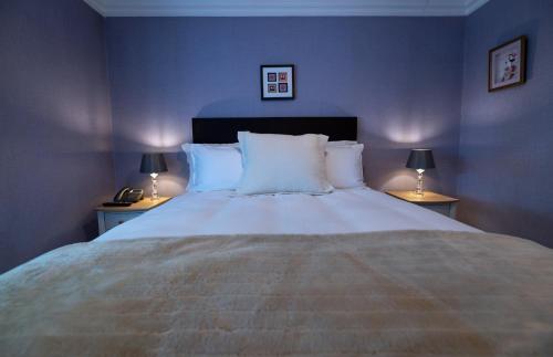 a blue bedroom with a large bed with two lamps at Charnwood Guest House in Bracknell