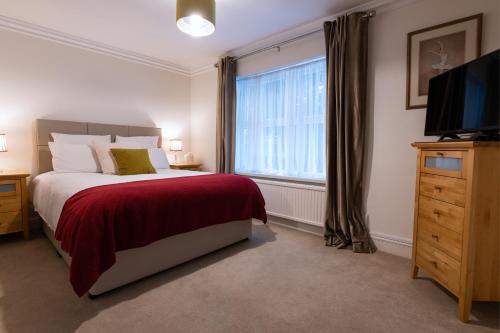 1 dormitorio con 1 cama, TV y ventana en Charnwood Guest House, en Bracknell