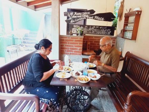 a man and woman sitting at a table eating food at Mama Villa Hikkaduwa in Hikkaduwa