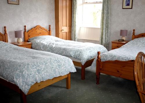 a bedroom with three beds and a window at Ullathorns Farm in Kirkby Lonsdale