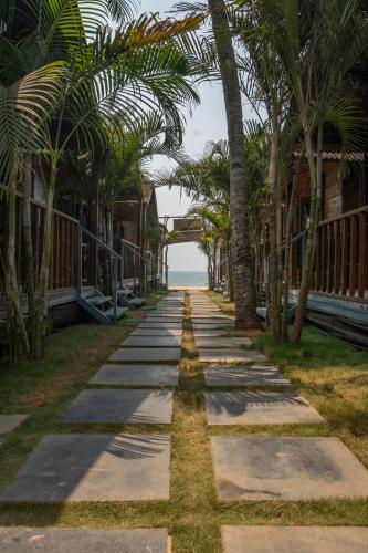 a sidewalk lined with palm trees next to the ocean at Shambho Retreat in Canacona