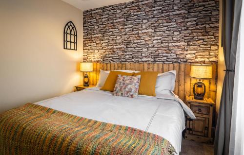 ein Schlafzimmer mit einem Bett und einer Steinmauer in der Unterkunft Cornish Tin Mine Themed Apartment in St Austell