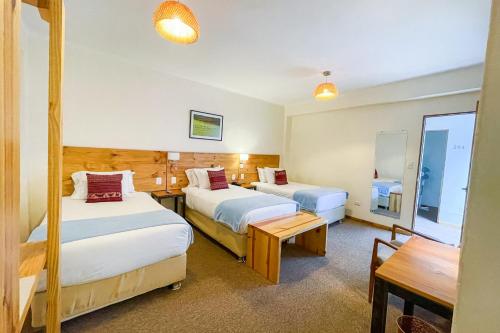 a hotel room with two beds and a table at Cooper Hotel Boutique in Cusco