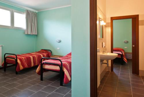 a room with two beds and a sink and a mirror at Casthello Ostello di Vallecamonica in Breno