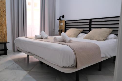 a bedroom with a large bed with white sheets and pillows at Planeta Cadiz Hostel in Cádiz