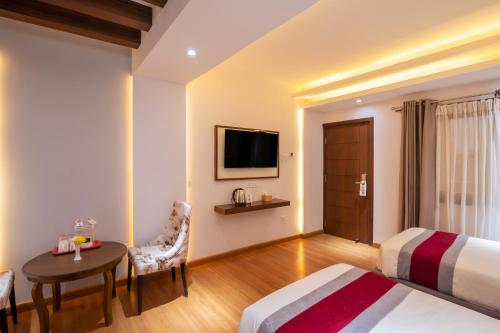 a hotel room with a bed and a table and a television at Hotel Ama-La, Thamel, Kathmandu in Kathmandu