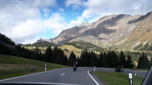 zwei Personen, die auf einer Straße in den Bergen Motorrad fahren in der Unterkunft Alps Oriental Wellness HOTEL in Campodolcino