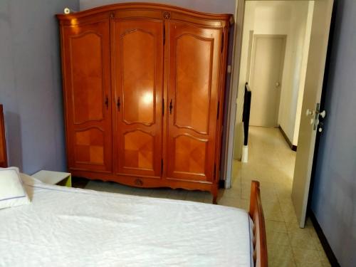 1 dormitorio con armario de madera junto a la cama en paradis des randonneurs, en Roquefort-des-Corbières