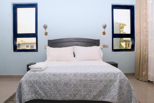 a bedroom with a bed and two windows at Candide Guest House in Limbe