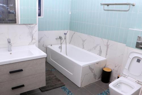 La salle de bains est pourvue d'une baignoire, d'un lavabo et de toilettes. dans l'établissement Candide Guest House, à Limbe