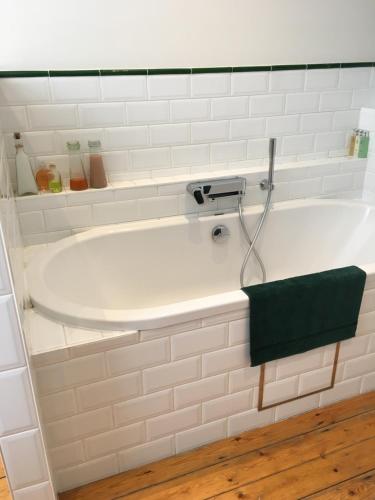 een wit bad met een groene handdoek erop bij Overijse’s cosiest double room in Overijse