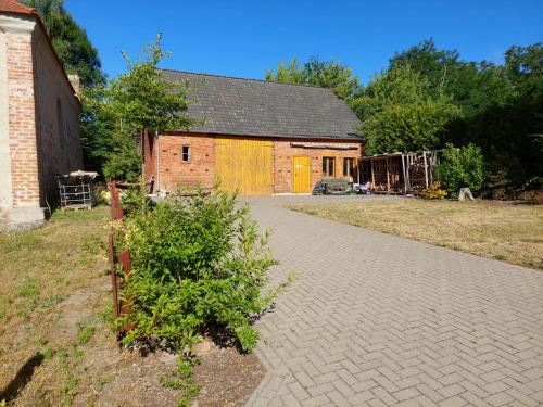 a brick barn with a building in the background at Altmark - Haus am Hang mit Garten 