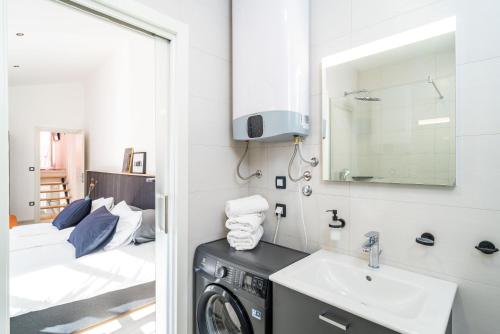 ein Bad mit einer Waschmaschine, einem Waschbecken und einem Bett in der Unterkunft Cavtat Old School in Cavtat