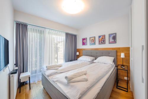 a bedroom with a large bed and a large window at Apartamenty Sun & Snow Art Deco Gdynia in Gdynia