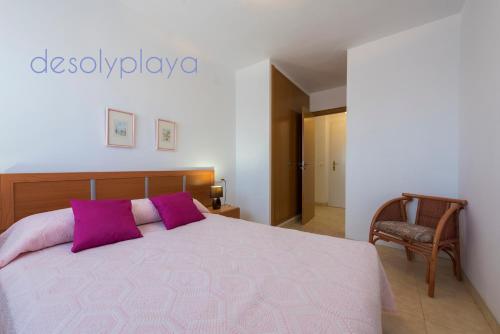 a bedroom with a bed with purple pillows and a chair at desolyplaya Colomeras 3T in Oropesa del Mar
