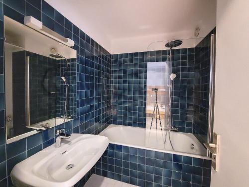 une salle de bain carrelée bleue avec un lavabo et une baignoire dans l'établissement RELAIS s30, à Saint-Jean-dʼAulps