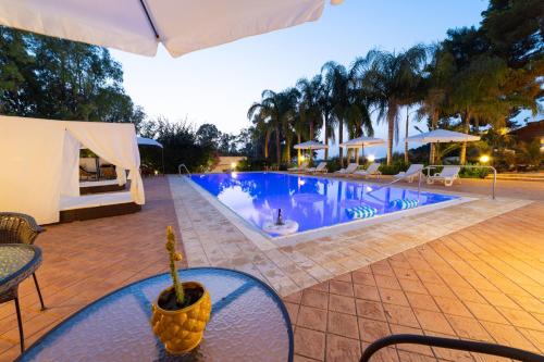 a swimming pool with chairs and a table and an umbrella at Villa Rosemary in Marsala