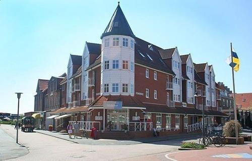 un gran edificio marrón y blanco con una torre en Inselresidenz Strandburg Juist Ferienwohnung 50955, en Juist
