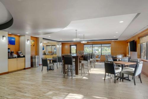 a dining room with tables and chairs and a kitchen at Comfort Suites Stockbridge Atlanta South in Stockbridge